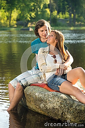 Smiling couple sitting on a rock romantic Stock Photo