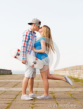 Smiling couple with skateboard kissing outdoors Stock Photo