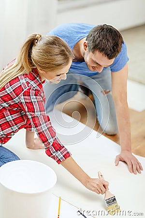 Smiling couple smearing wallpaper with glue Stock Photo