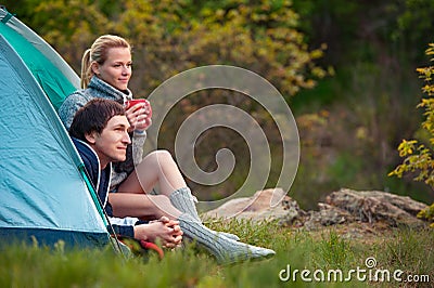 Smiling couple of tourists with cup of tea talking near the tent Stock Photo