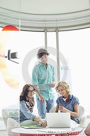 Smiling creative businesspeople discussing over laptop in office Stock Photo