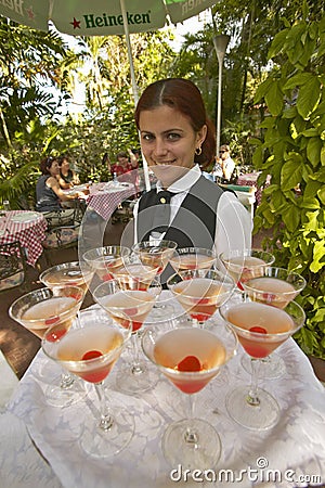 A smiling Cuban woman offering a tray of drinks at tourist restaurant in Havana Cuba Editorial Stock Photo