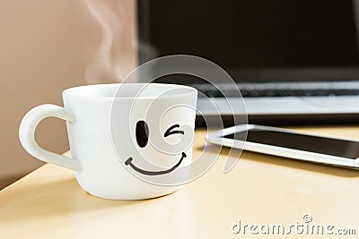 Smiling cup, smartphone and laptop on the desk Stock Photo