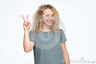 Smiling curly caucasian female model doing peace Stock Photo