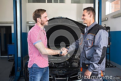 Smiling customer and mechanic shaking hands Stock Photo