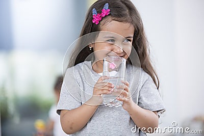 Smiling cute girl holding glass of water at home Stock Photo