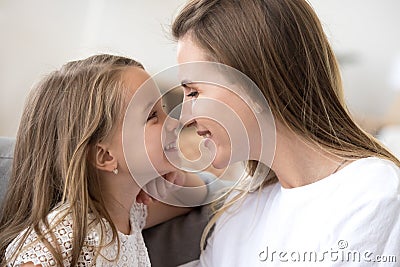 Smiling cute kid girl and mother touching noses expressing tende Stock Photo