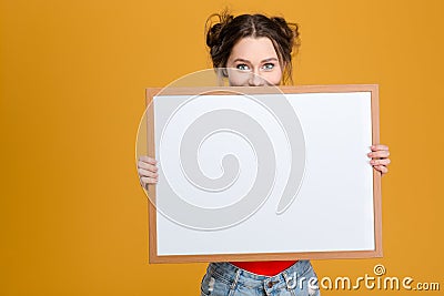 Smiling cute lovely young woman hiding behind blank board Stock Photo