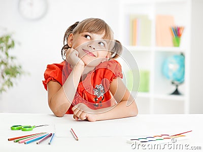 Smiling cute schoolgirl dreaming making homework Stock Photo