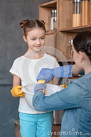 Smiling daughter helping mother with housework at home Stock Photo