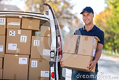 Smiling delivery man loading boxes into his truck Stock Photo