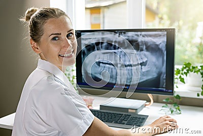 smiling dentist working with dental x-ray image on computer in clinics office Stock Photo