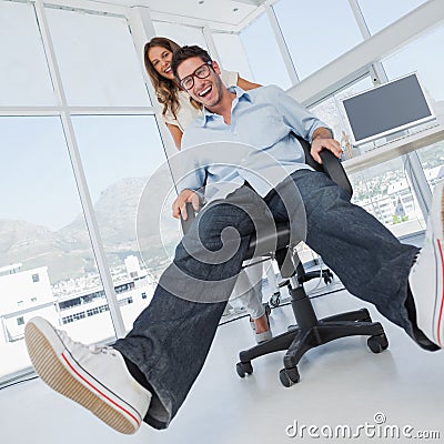 Smiling designers having fun with on a swivel chair Stock Photo