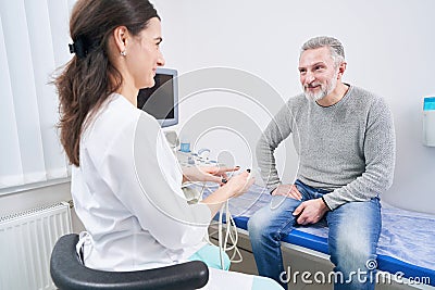 Friendly young sonographer communicating with patient before ultrasonography Stock Photo