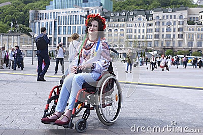 Smiling disabled woman in Ukrainian Embroidered shirt and native red circlet of flowers sitting in a wheelchair on the street Editorial Stock Photo