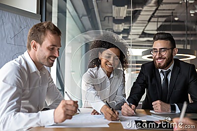 Smiling diverse businesspeople consider financial paperwork at briefing Stock Photo