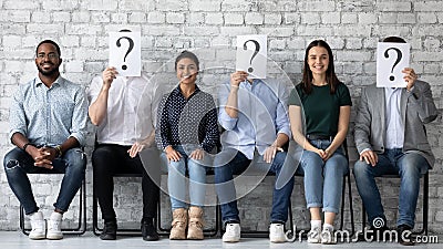 Smiling diverse candidates sitting in row with unknown people Stock Photo