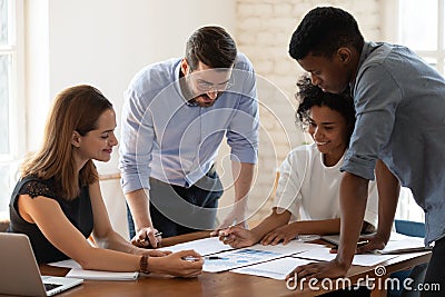 Smiling diverse colleagues discuss paperwork at meeting Stock Photo