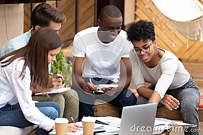 Smiling diverse friends doing paperwork together in cafe Stock Photo