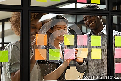 Smiling multiracial colleagues develop project on sticky notes Stock Photo