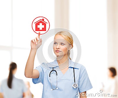 Smiling doctor or nurse pointing to hospital icon Stock Photo