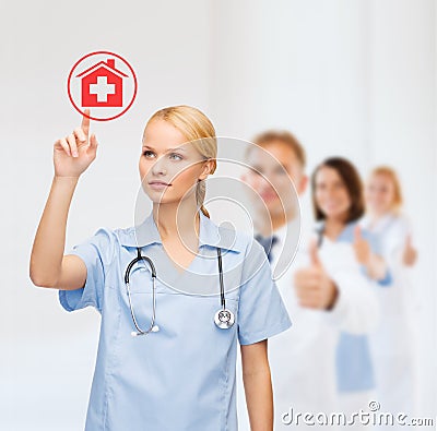 Smiling doctor or nurse pointing to hospital icon Stock Photo