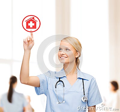 Smiling doctor or nurse pointing to hospital icon Stock Photo