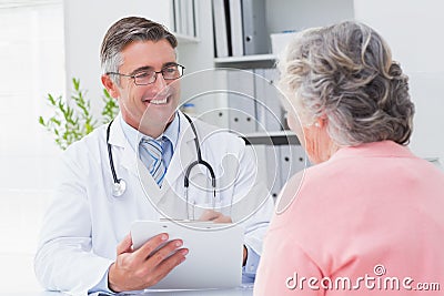 Smiling doctor writing prescriptions for patient Stock Photo