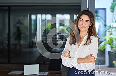 Smiling Latin professional mid aged business woman looking away in office. Stock Photo