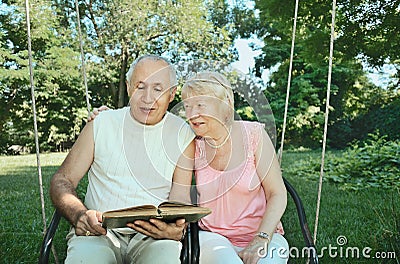 Smiling elderly man and woman 65-69 years old absorbedly readi Stock Photo