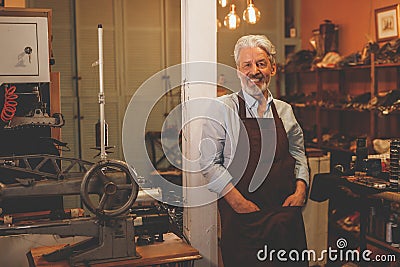 Smiling elderly shoemaker in uniform Stock Photo