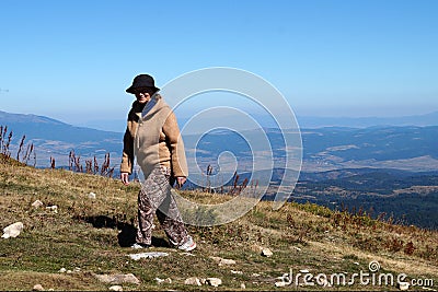 Smiling elderly woman climb the mountain on a sunny day Stock Photo