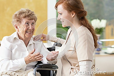 Smiling elderly woman talking with friendly caregiver in the nursing house Stock Photo