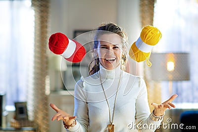Smiling elegant woman throwing up yellow and red yarn Stock Photo