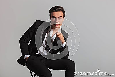 Smiling elegant man in tuxedo and undone bowtie sitting Stock Photo