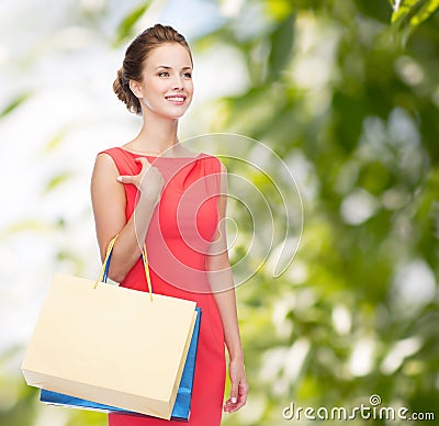 Smiling elegant woman in dress with shopping bags Stock Photo