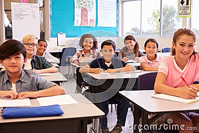 Smiling elementary school kids sitting at desks in classroom Stock Photo