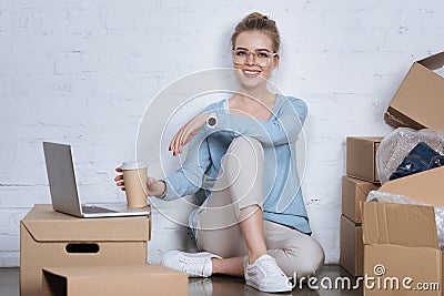 smiling entrepreneur with coffee to go sitting on floor Stock Photo