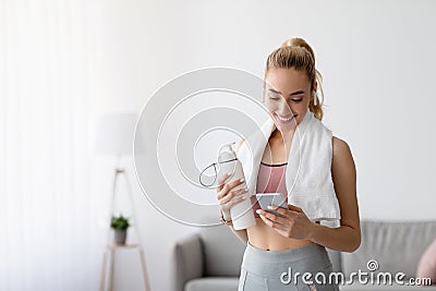 Smiling european cute young woman athlete with bottle of water check fitness app or social networks on smartphone Stock Photo