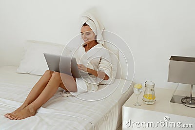 Smiling european girl use laptop while lay on bed Stock Photo