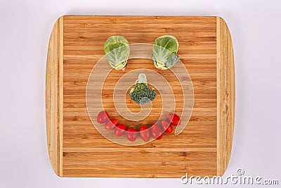 Smiling face made of Brussel sprouts broccoli floret cherry tomatoes Stock Photo