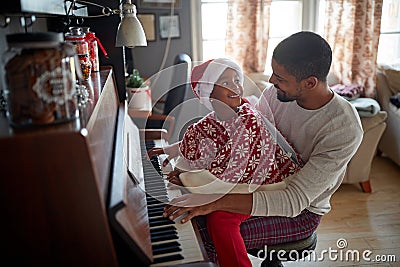 Family on Christmas morning play music on piano Stock Photo