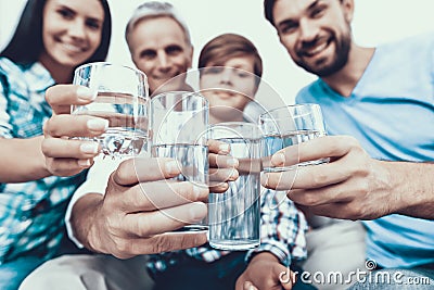 Smiling Family Drinking Water in Glasses at Home. Stock Photo