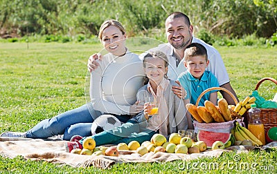 Smiling family of four having a picnic outdoors Stock Photo