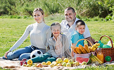 Smiling family of four having a picnic outdoors Stock Photo