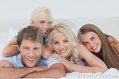 Smiling family lying on bed Stock Photo