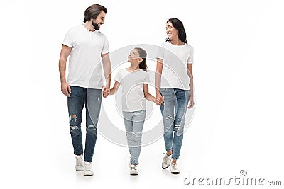 smiling family in white shirts and jeans holding hands while walking together Stock Photo