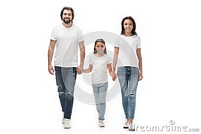smiling family in white shirts and jeans holding hands while walking together Stock Photo