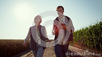 Smiling farmers walking farmland on sunny day. Happy agrarian team at field. Stock Photo