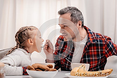 smiling father feeding adorable little girl Stock Photo